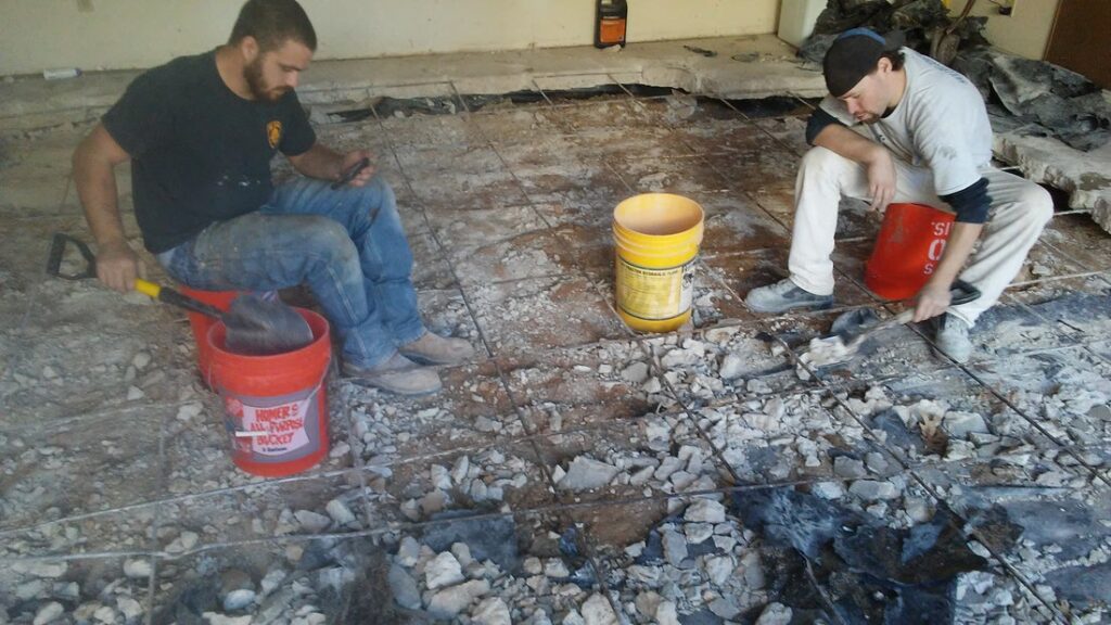 Workers remove broken concrete during slab crack repair process
